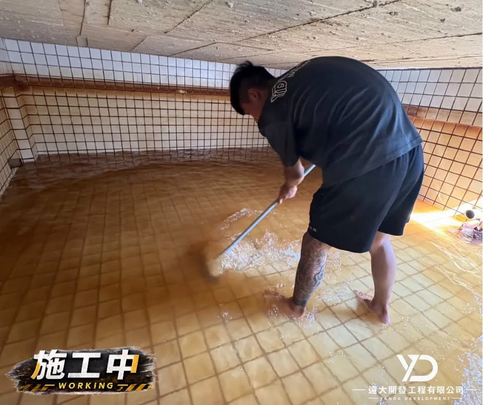 施工人員刷洗水塔底部磁磚與沉積污垢