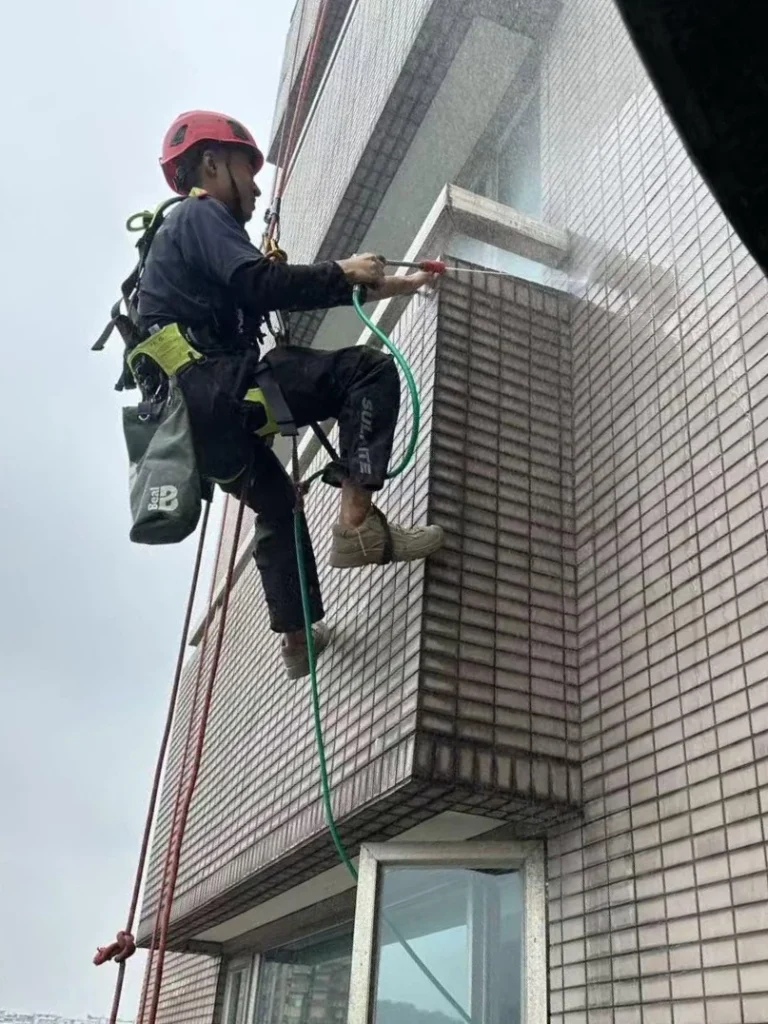 高空繩索技術人員使用高壓水柱清洗大樓磁磚外牆