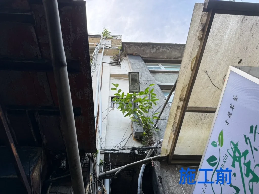 基隆自來街外牆施工前,建物高處與側巷可見花木雜草生長