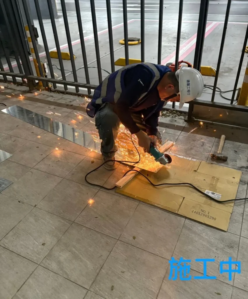 中興國小停車場欄杆施工中，人員依尺寸切割底部封板
