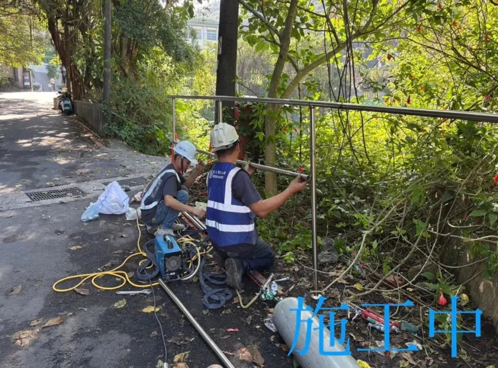 銘傳國中白鐵欄杆施工中，兩名人員定位新欄杆框架