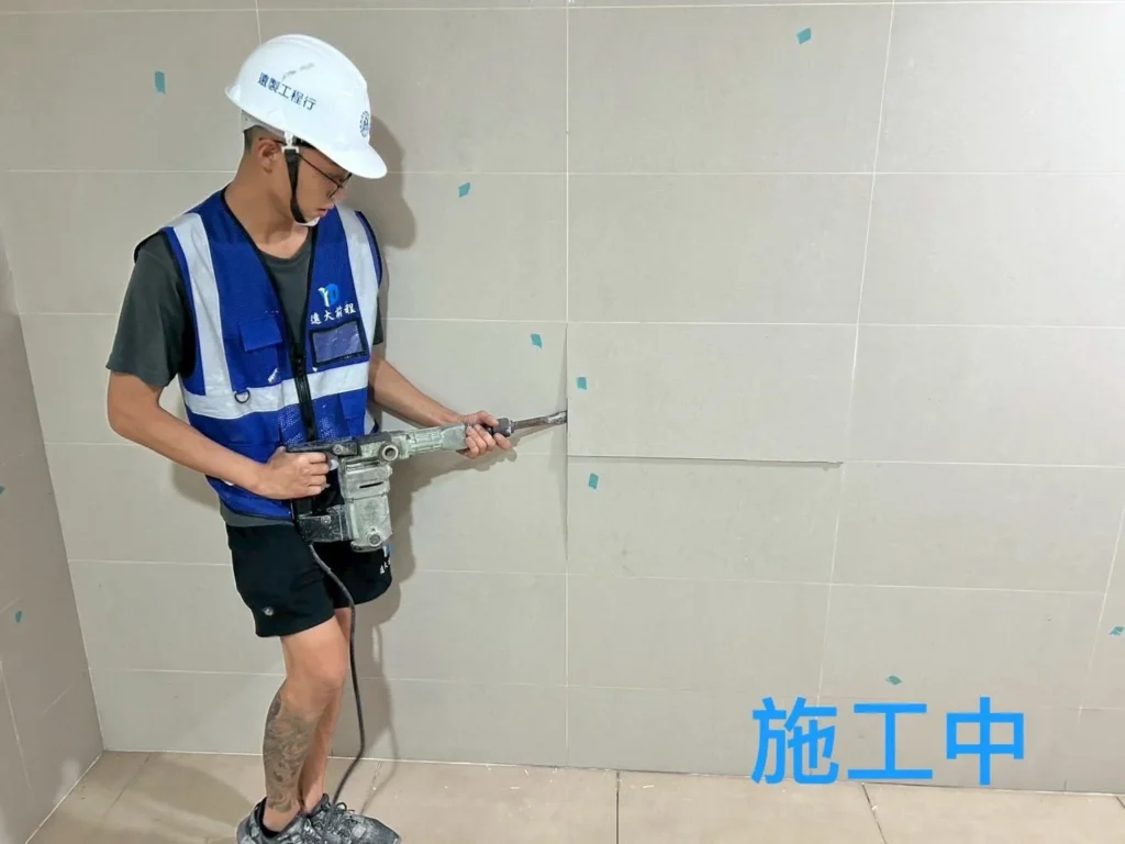 社區牆面磁磚施工中,人員使用電動工具整理貼磚範圍