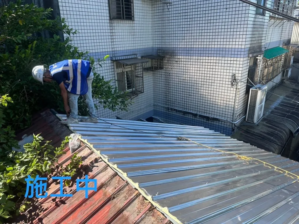 基隆獅球路屋頂換板施工中,人員鋪設銀色白鐵浪板