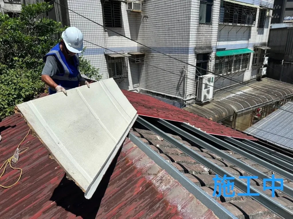 獅球路鐵皮屋頂更換施工中,人員搬移拆下的大型舊板材