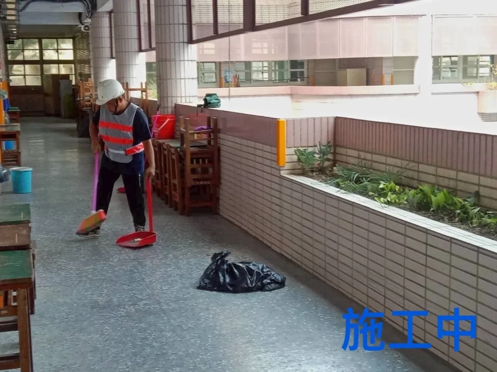 中和國小走廊清潔施工中,人員以掃把清除地面髒汙