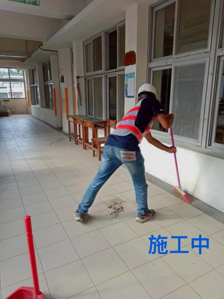 中和國小走廊清潔施工中,人員拖洗淺色磁磚地坪