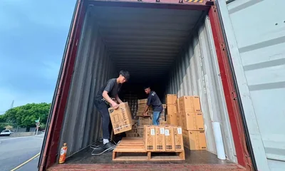 物流人員在貨櫃內協作搬運紙箱與棧板貨物