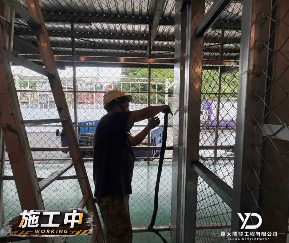 台基國際物流網牆施工中,作業人員於梯具旁整理金屬框架安裝位置