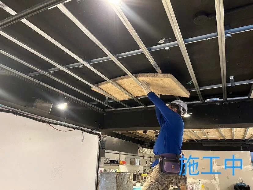台北中山區暗架天花施工中,作業人員將填充板材放入天花骨架