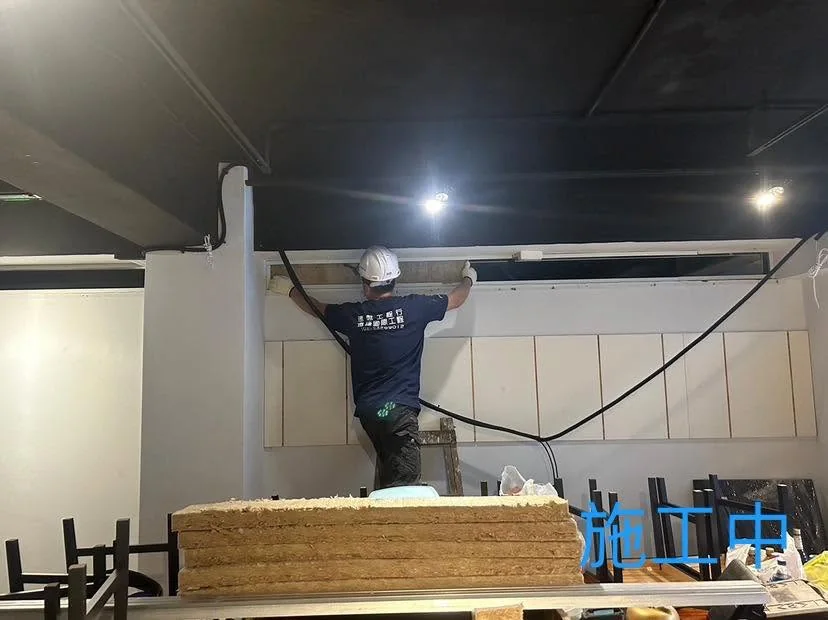 台北中山區輕隔間施工中,作業人員安裝上方橫向板材並調整線路