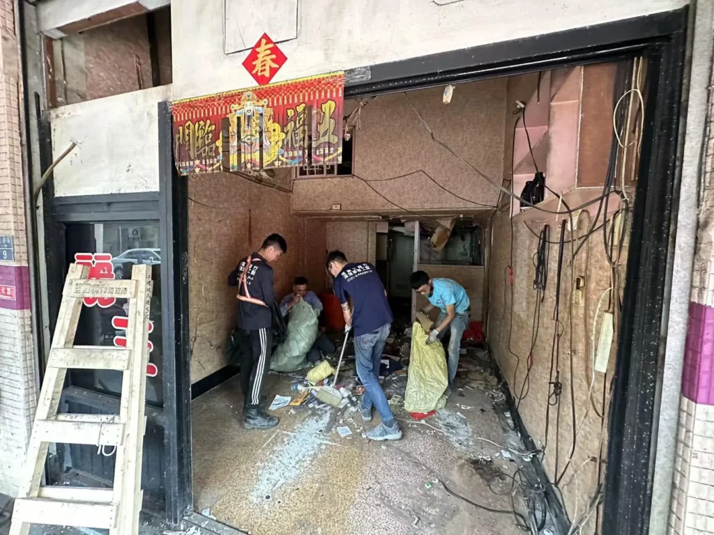 基隆仁愛區老屋清運施工中,多名作業人員清掃並裝袋室內零散廢棄物