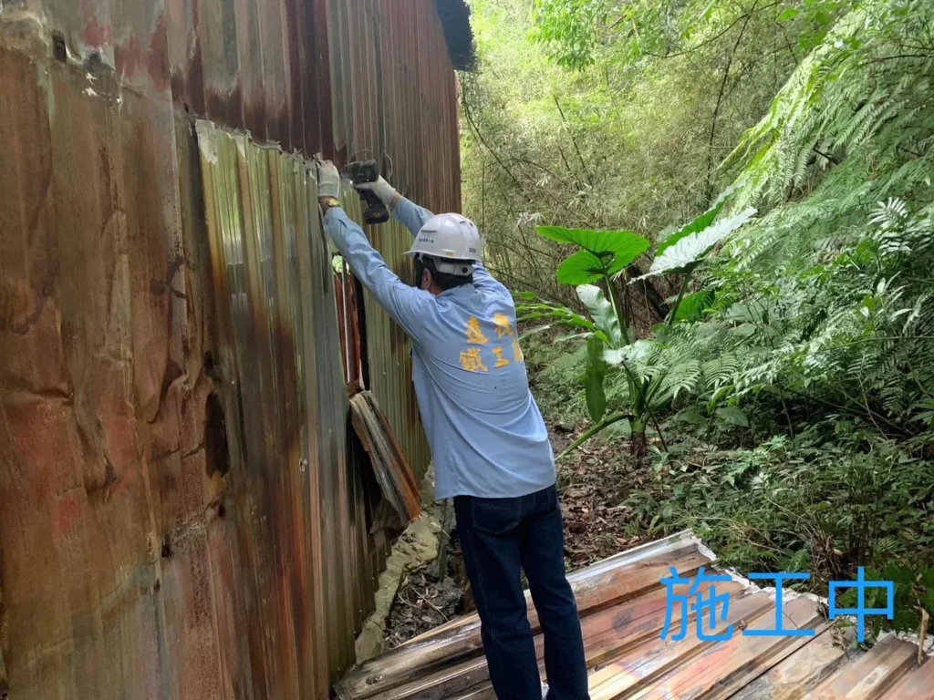 汐止靈隱寺災後鐵工重建施工中,作業人員拆卸建物外側鏽蝕牆面浪板