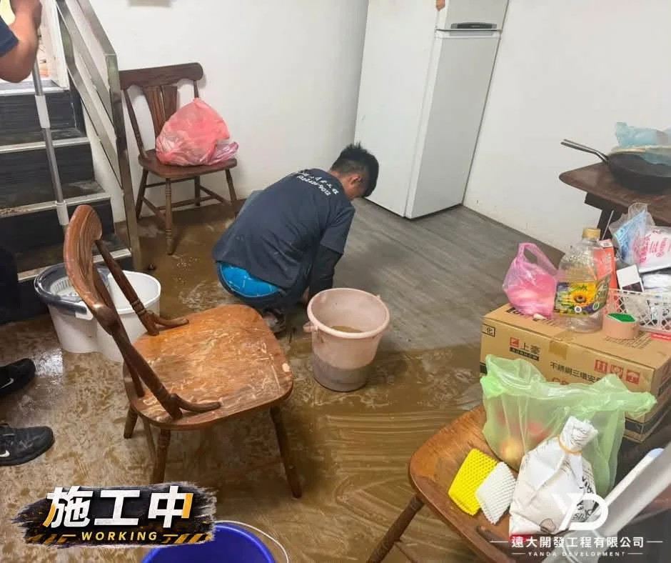 基隆市仁愛區災後清理施工中，人員蹲地刷洗客廳積水與泥沙